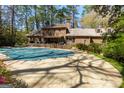 Spacious backyard with a covered in-ground pool, brick patio, and lush landscaping at 9995 Huntcliff Trce, Atlanta, GA 30350