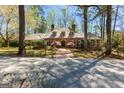Charming brick home featuring a wood roof, dormer windows, mature trees, and a welcoming brick walkway at 9995 Huntcliff Trce, Atlanta, GA 30350