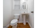 Well-lit half bath featuring a pedestal sink, wood flooring, and a window for natural light at 1870 Wildcat Trace Cir, Lawrenceville, GA 30043