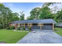 Attractive single-story home with a combination of brick and gray siding, a well-maintained lawn, and mature trees at 1091 Pine St, Conyers, GA 30012