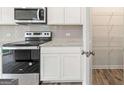 Clean kitchen with stainless steel range, microwave, white cabinets, and granite countertops at 8504 Polston Pl # 145, Douglasville, GA 30134