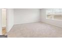 Bright bedroom with a neutral carpet, large window, and adjacent bathroom at 8501 Polston Pl # 143, Douglasville, GA 30134