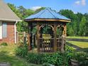 Wooden gazebo with metal roof in backyard, surrounded by lush greenery and fencing at 2585 Old Jackson Rd, Locust Grove, GA 30248