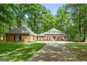 Beautiful brick home featuring a spacious driveway, mature trees, and lush green landscaping on a sunny day at 145 Oxford Ln, Fayetteville, GA 30215