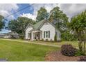 Quaint home with green roof and shutters, complemented by mature trees and a well-manicured lawn at 111 S Old 27, Roopville, GA 30170