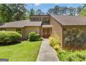 Close-up of the home's entrance, featuring a unique front door, well-kept lawn and mature shrubs at 105 Gleneagles Pt, Peachtree City, GA 30269