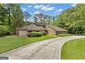 Inviting single-story home featuring a long driveway and lush green lawn surrounded by mature trees at 105 Gleneagles Pt, Peachtree City, GA 30269