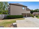 Side view of house featuring an attached three-car garage and well-maintained backyard landscaping at 3823 Heritage Pl, Buford, GA 30519
