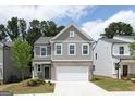 Charming two-story home with gray siding, brick accents, and a two-car garage under a partly cloudy sky at 407 Newland Way, Acworth, GA 30102
