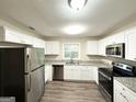 Modern kitchen featuring white cabinets, stainless steel appliances, granite countertops and plank flooring at 2860 Lynda Pl, Decatur, GA 30032