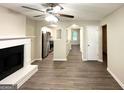 Open living room with fireplace, ceiling fan, and hardwood floors leading into kitchen at 614 Tramore Ct, Stockbridge, GA 30281