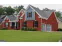 Beautiful two-story red brick home with a well-manicured lawn, dark shutters and a two-car garage at 141 Windward Hills, Mcdonough, GA 30253