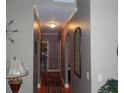 Inviting hallway featuring hardwood floors, neutral walls, arched entryways, and elegant lighting at 141 Windward Hills, Mcdonough, GA 30253