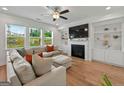 Cozy living room featuring hardwood floors, fireplace, built-in shelves, and large windows at 5350 Woodline View Cir, Hoschton, GA 30548