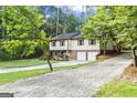 View of the home's front exterior with a two-car garage and gravel driveway entrance at 2687 Fairfield Sw Dr, Marietta, GA 30064