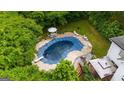 Aerial view of a covered in-ground pool surrounded by a patio, table with umbrella, chairs and lush greenery at 2810 Jodeco Ter, Jonesboro, GA 30236