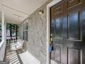 Cozy covered porch with a white swing, stone wall, and black front door creates a welcoming entrance at 11203 Hemlock Rd, Hampton, GA 30228