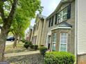 View of multiple brick townhomes with black shutters, sidewalks, and landscaping at 1843 Grove Way, Hampton, GA 30228