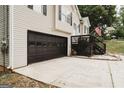 Side view of a home with a two-car garage, dark trim and stairs leading to a front deck at 228 Hunt Club Cir, Temple, GA 30179