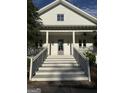 View of the large front porch and gray front door of this charming two-story home at 10583 Serenbe Ln, Palmetto, GA 30268