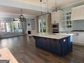 Open-concept kitchen featuring a large blue island, stainless steel appliances, and hardwood floors at 10583 Serenbe Ln, Palmetto, GA 30268