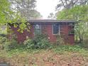 A brick home exterior showcases dual windows, complemented by climbing vines and lush greenery at 4720 Ben Hill Rd, South Fulton, GA 30349