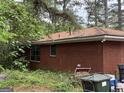 Exterior of a brick home including the side view of the house, windows, yard debris and trees at 4720 Ben Hill Rd, South Fulton, GA 30349