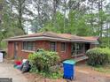 Exterior view of the house featuring a classic brick facade, a front porch, and some yard debris at 4720 Ben Hill Rd, South Fulton, GA 30349