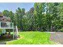 Expansive backyard featuring a large grassy area, mature trees, and a partially covered patio at 20 Allie Dr, Mcdonough, GA 30252