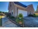 Side view of home featuring a two-car garage, brick exterior, and landscaped pathway at 3008 Brighton Ct, Conyers, GA 30094