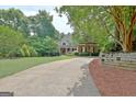 Beautiful landscaped home exterior with a long driveway lined with mature trees and lush greenery at 102 Passage Point, Peachtree City, GA 30269