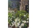 Ashley Falls community entrance with stone pillars, a hanging sign, and lush white flowers at 7253 Lacey Dr, Douglasville, GA 30134