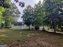 Back exterior view of home surrounded by mature trees and a lush, green lawn at 7640 Ryefield Dr, Sandy Springs, GA 30350