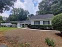 Ranch-style home with a white brick exterior, well-maintained landscaping, and a concrete pathway leading to the front door at 7640 Ryefield Dr, Sandy Springs, GA 30350