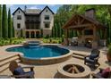 Resort-style backyard oasis with a pool, hot tub, outdoor kitchen, fireplace, and lush landscaping for ultimate relaxation at 10765 Shallowford Rd, Roswell, GA 30075
