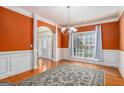 Formal dining room featuring hardwood floors, orange walls, wainscoting, and decorative lighting at 145 Windward Hls, Mcdonough, GA 30253