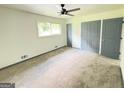 Bright, carpeted bedroom with a ceiling fan and large closets at 7340 Chalk Way, Riverdale, GA 30296