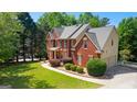 A view of the red brick exterior showcasing the home's architectural details and side-entry garage at 255 Hidden Lake Dr, Fayetteville, GA 30215