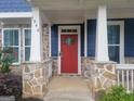 Close-up of the home's entry featuring a red front door, stone accents, and a covered porch with white pillars at 1946 Jeffery Nw Rd, Atlanta, GA 30318