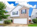 Two-story home featuring a brick and siding exterior, two-car garage, and manicured landscaping at 1562 Onalee Dr, Hampton, GA 30228