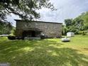 View of the back of the stone house with a propane tank and shed in the large yard at 1085 Pleasant Hill Nw Rd, Conyers, GA 30012