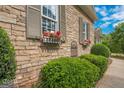 Home's exterior showcasing stone accents, manicured bushes, and window boxes filled with colorful flowers at 531 Grant Rd, Brooks, GA 30205