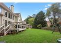 Expansive backyard featuring a lush lawn, a wooden deck, and a playground set, ideal for outdoor activities at 1029 Ector Nw Dr, Kennesaw, GA 30152