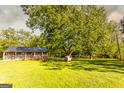 Exterior view of a cabin with a large wooden porch surrounded by lush green lawn and mature trees at 316 Gaithers Rd, Mansfield, GA 30055
