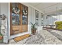 A cozy porch with brick floor and hanging swing, complemented by double doors with floral wreaths at 415 Discovery Lake Dr, Fayetteville, GA 30215