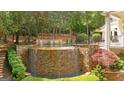 Stunning backyard pool featuring a rock waterfall feature and professionally landscaped garden at 8957 Old Southwick Pass, Johns Creek, GA 30022