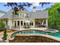 Inviting backyard with stone-lined pool, patio seating, outdoor lounge, and upper level balcony at 8957 Old Southwick Pass, Johns Creek, GA 30022