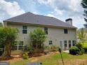 Two-story home with many windows, a grey roof, a chimney and landscaped yard with mature trees at 75 Trelawney Keep, Covington, GA 30016