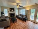 Cozy living room with stone fireplace, ceiling fan, and access to the backyard at 110 Shelby Oaks Trl, Covington, GA 30016