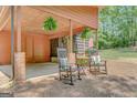 Inviting carport space with rocking chairs and hanging ferns, creating a cozy outdoor area at 29 Clark Pl, Whitesburg, GA 30185
